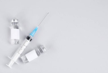 Cam şişelerde aşı ve gri arka planda şırınga düz yerde. Metin için boşluk