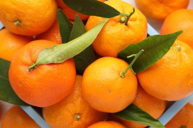 Taze mandalina ve yeşil yapraklar masada, yakın plan.