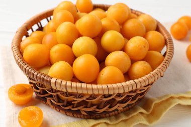 Beyaz ahşap masada olgun sarı erikler, yakın plan.