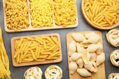 Gri masada farklı türde çiğ makarna, düz yatıyordu.