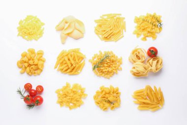 Farklı türde çiğ makarna, domates, biberiye ve kekik beyaz masada, düz yerde.