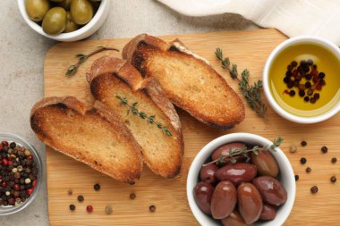 Baget, yağ, baharat ve zeytin dilimleri açık gri masada, düz yerde.