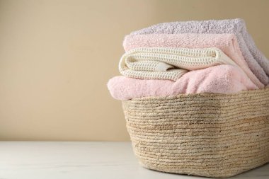 İçerideki bej duvarın yanındaki ışıklı masanın üzerinde havlular olan çamaşır sepeti. Metin için boşluk