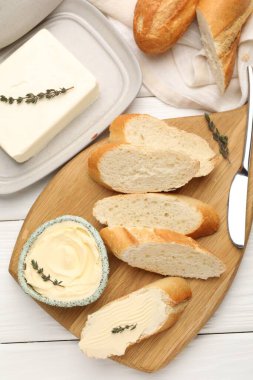 Tereyağlı baget dilimleri, kekik ve bıçak beyaz ahşap masada, düz yatıyordu.