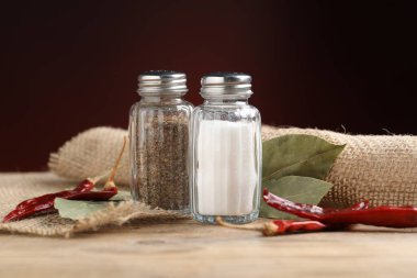 Ahşap masada baharatlı tuzluk ve biberlikler koyu arka planda, yakın planda.