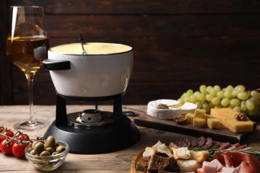 Lezzetli eritilmiş peynirli fondü, abur cuburlar ve ahşap masada şarap. Metin için boşluk