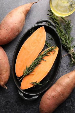 Çiğ patates, biberiye ve yağ siyah masada, düz yerde.