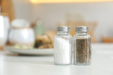 Beyaz masa içerisindeki baharatlı tuzluk ve biberlikler, yakın plan. Metin için boşluk