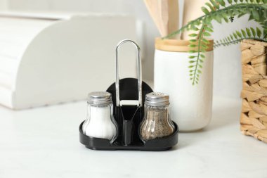 Beyaz masadaki baharatlı tuzluklar ve biberlikler, yakın plan.