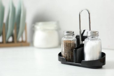 Beyaz masa içerisindeki baharatlı tuzluk ve biberlikler, yakın plan. Metin için boşluk