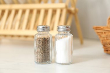 Beyaz masadaki baharatlı tuzluklar ve biberlikler, yakın plan.