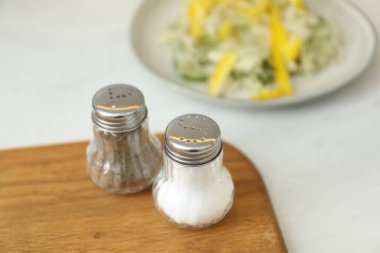 Beyaz masada baharatlı tuzluk ve biberlikler, yakın plan.