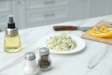 Baharatlı tuzluk, biberlik, salata, yağ ve kapalı alandaki beyaz mermer masada dolmalık biber.