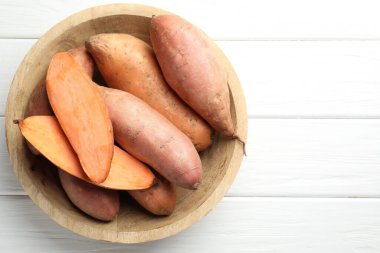 Beyaz ahşap masadaki kasede çiğ patates, üst manzara. Metin için boşluk