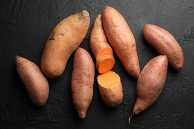 Siyah desenli masada çiğ patates, düz uzanmış.