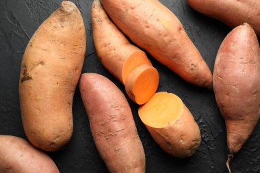 Siyah desenli masada çiğ patates, düz uzanmış.