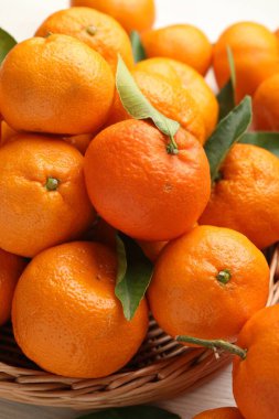 Taze mandalina ve yeşil yapraklar açık ahşap masada, yakın plan.