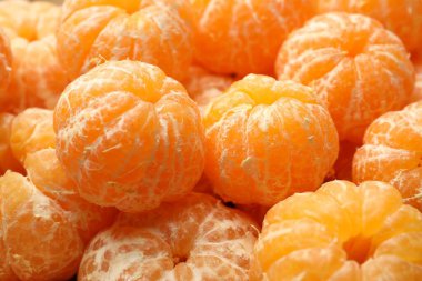 Arka plan olarak birçok olgun soyulmuş mandalina, yakın plan