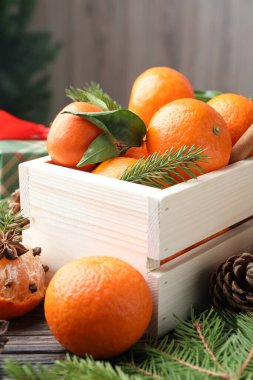 Olgun mandalinalar, baharatlar ve köknar dalları ahşap masada, yakın plan.