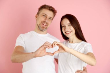 Pembe arka planda elleri olan, seçici odaklı mutlu çift.