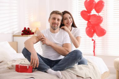 Yataktaki mutlu çift kalp şeklinde balonlarla süslenmiş. Sevgililer Günü kutlaması