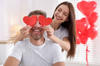 Kapalı alanda kağıt kalpli mutlu bir çift. Sevgililer Günü kutlaması