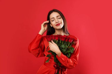 Sevgililer Günü. Kırmızı arka planda gül buketi olan güzel bir kadın.