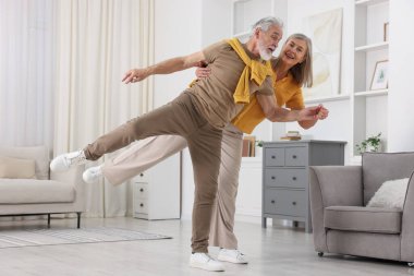 Mutlu yaşlı çift evde dans ediyor.