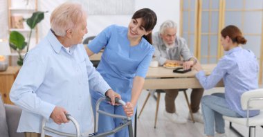 Huzurevinde yaşlı kadına Walker 'la yardım eden bakım işçisi.