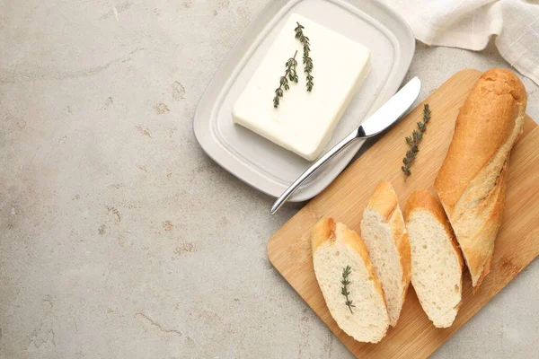 Tereyağlı baget ekmek, kekik ve bıçak gri desenli masa, düz yatak. Metin için boşluk