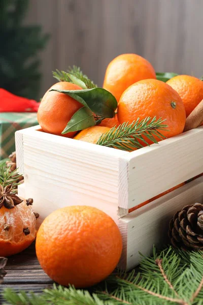 Olgun mandalinalar, baharatlar ve köknar dalları ahşap masada, yakın plan.