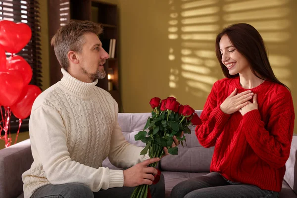 Mutlu adam içeride gül buketiyle kız arkadaşına sürpriz yapıyor. Sevgililer Günü kutlaması