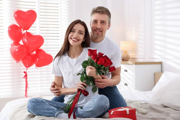 Yataklarında gül buketi olan mutlu bir çift. Sevgililer Günü kutlaması