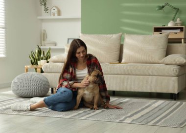 Evdeki kanepenin yanında sevimli köpeği olan bir kadın.