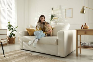 Evdeki kanepede tatlı köpeğiyle dinlenen bir kadın.