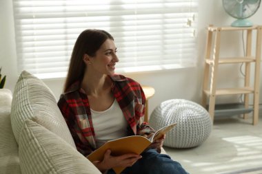 Dergisi olan kadın evdeki kanepede dinleniyor.