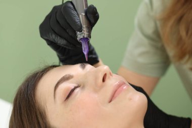 Güzellik uzmanı genç bir kadına göz kalemi yapıyor. Kapalı mekanda, yakın plan.