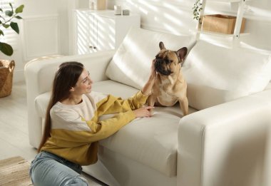 Evdeki kanepenin yanında tatlı köpeği olan bir kadın.