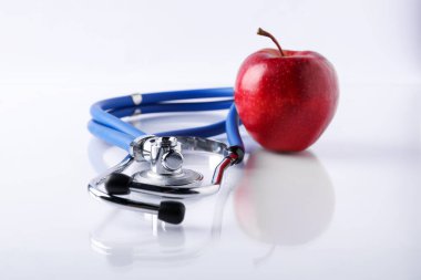 Olgun elma ve steteskop beyaz masada, yakın plan.