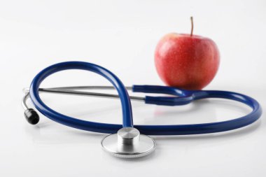 Olgun elma ve steteskop beyaz masada, yakın plan.
