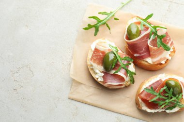 Krem peynirli nefis bruschettalar, prosciutto, zeytin ve roka, gri dokulu masa, üst manzara. Metin için boşluk
