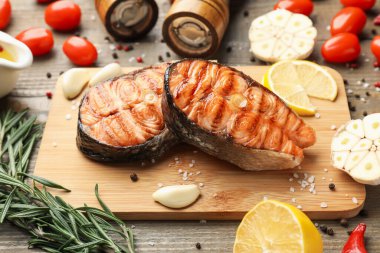 Ahşap masada servis edilen lezzetli ızgara somon biftekleri, yakın plan.