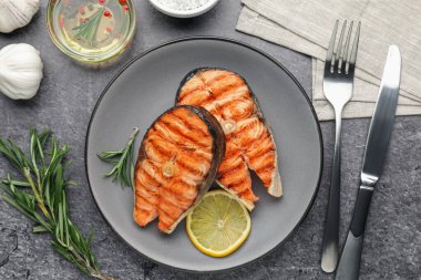 Lezzetli ızgara somon bifteği, limon ve biberiyeyle servis edilir.