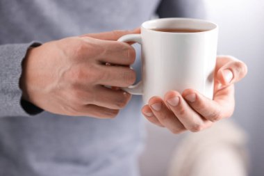 Kapalı mekanda bir fincan sıcak çay içen adam, yakın plan.