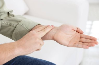 Adam nabzını evde kontrol ediyor, yakın plan. Metin için boşluk