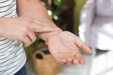 Adam nabzını evde kontrol ediyor, yakın plan.