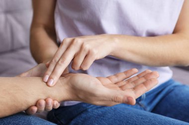 Kadın adamın nabzını kontrol ediyor. Parmakları evde, yakın plan.