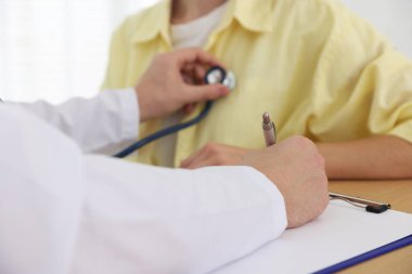 Doktor hastanede steteskopla kadının kalp atışlarını kontrol ediyor.