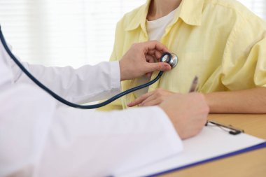 Doktor hastanede steteskopla kadının kalp atışlarını kontrol ediyor.