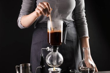 Siyah arka planda elektrikli süpürgeyle kahve yapan kadın, yakın plan.